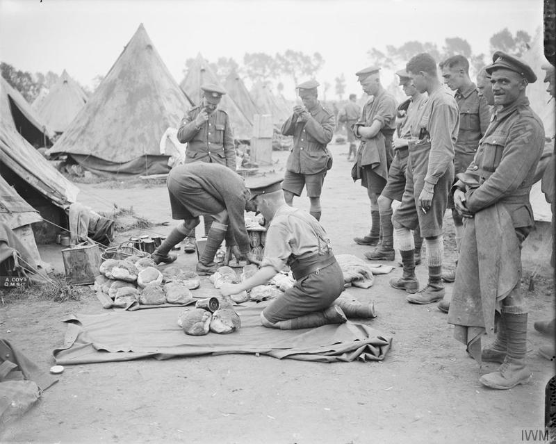 Troops of the 7th (Service) Battalion, Northamptonshire Regiment drawing rations from the Quartermaster's stores in a camp near Dickebusch, 9 August 1917. Imperial War Museum image Q5849